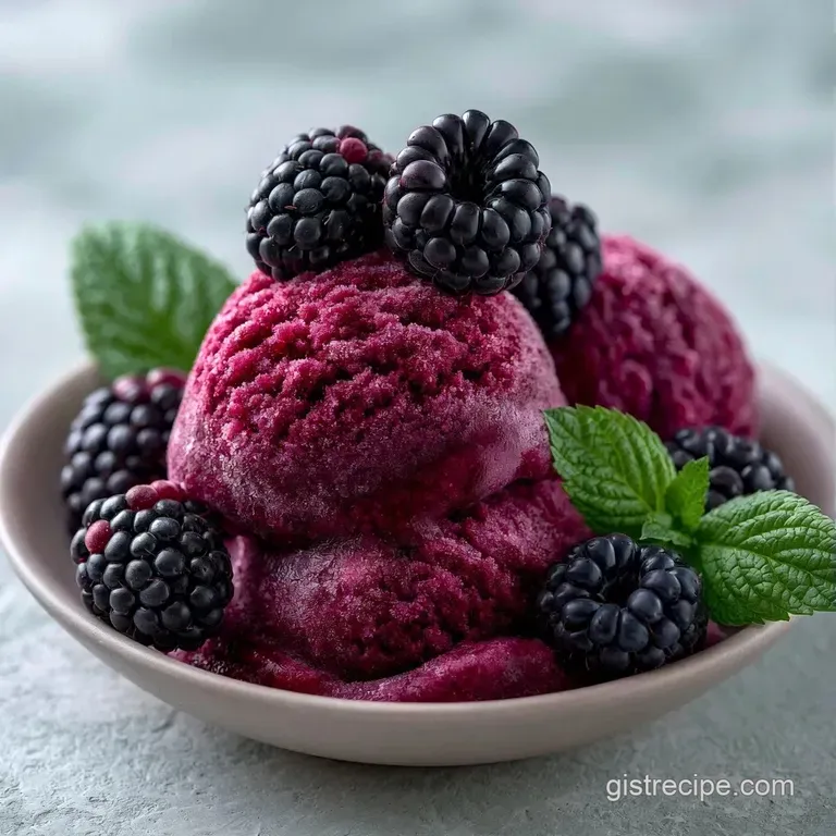Vibrant purple frozen dessert in an elegant chilled coupe glass, garnished with a fresh berry and mint leaf.