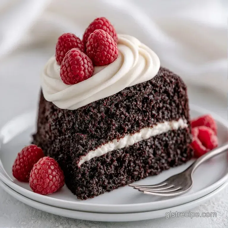 An elegant cake slice on a marble platter, adorned with tart fresh raspberries and a light dusting of powdered sugar.