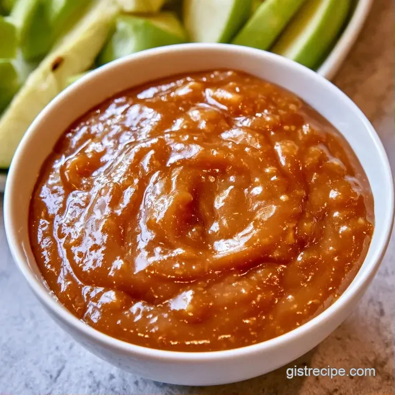 A rustic glass jar filled with amber-colored apple puree, topped with a cinnamon stick and a fresh apple slice.