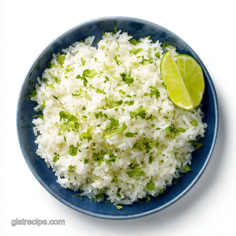 A mound of fluffy cilantro lime rice, garnished with a lime wedge and cilantro sprig, sits elegantly on a white plate.