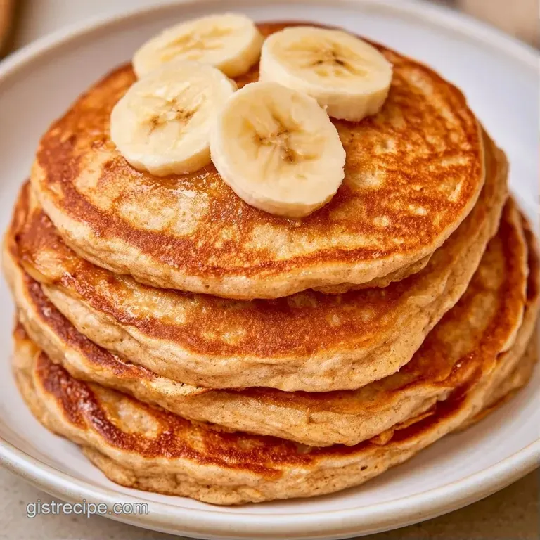 Elegant stack of warm golden pancakes on a matte plate, accented by sliced bananas and a dusting of cinnamon.