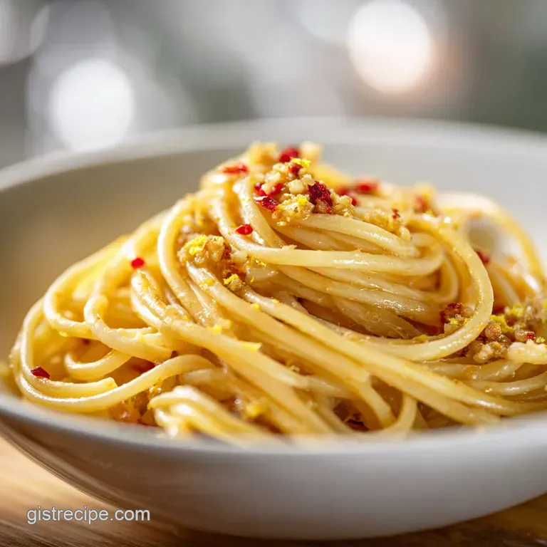 Elegant swirl of buttery noodles on a white plate, garnished with lemon wheels and a sprinkle of fresh herbs.