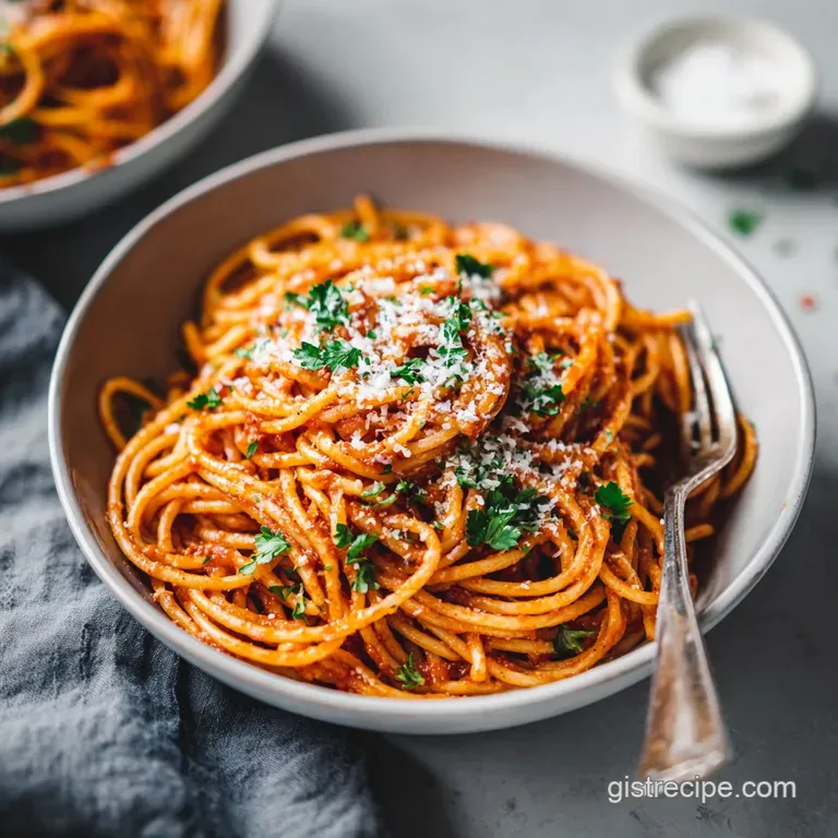 Al dente spaghetti twirls artfully on a white plate, bathed in a ruby-red sauce and garnished with parmesan.
