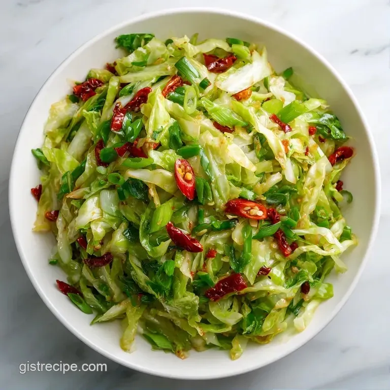 A heap of glistening cabbage and sliced peppers in a ceramic bowl, garnished with toasted sesame seeds and scallions.