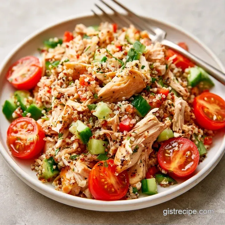 A neat mound of protein-rich grains and tender chicken topped with microgreens on a minimalist white porcelain plate.