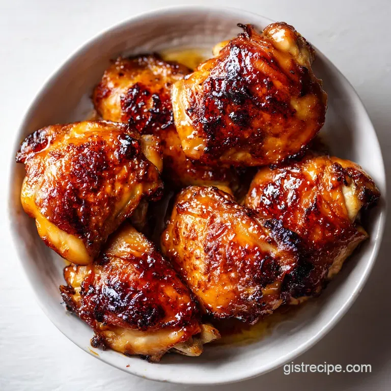 Glistening roasted chicken pieces arranged with bright lemon wedges and sprigs of fresh green rosemary on a white plate.