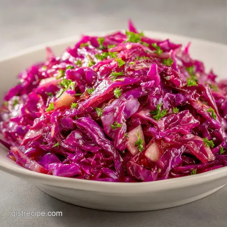A white ceramic bowl filled with deep magenta braised cabbage and tender apple slices, dusted with black pepper.