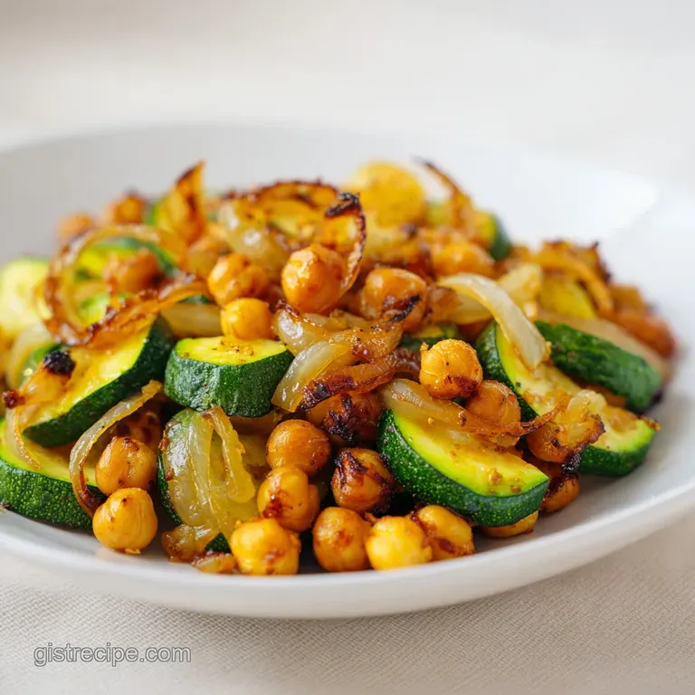 Elegant white plate with saut&eacute;ed green zucchini and golden chickpeas, topped with a sprinkle of fresh herbs.